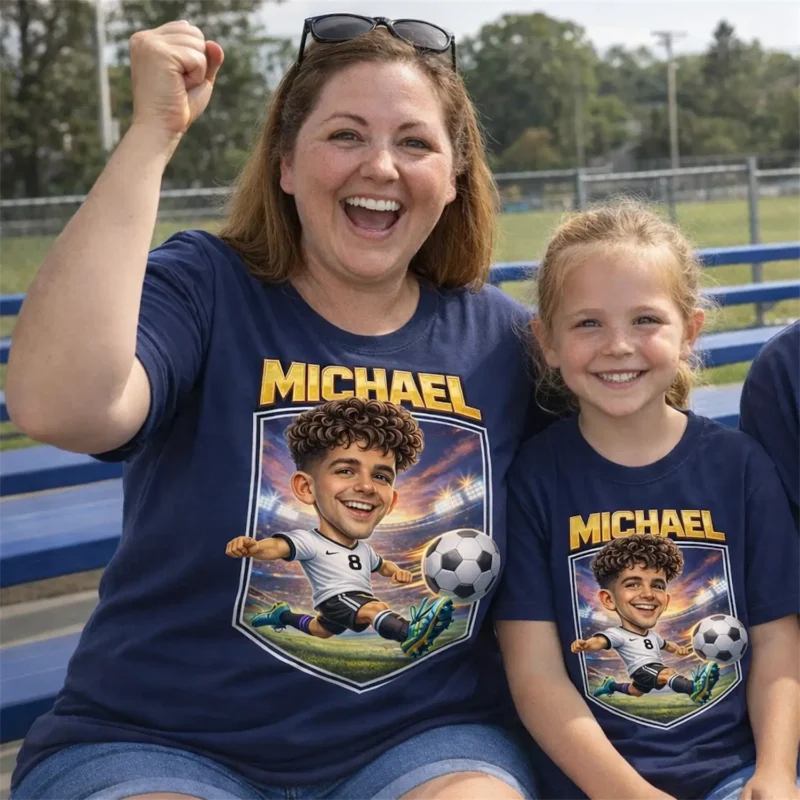 Celebrate your favorite player with this navy blue t-shirt featuring a custom soccer caricature. The artwork showcases name above a dynamic illustration of a soccer player mid-kick in a stadium setting. Designed for comfort and durability during long days at the field.